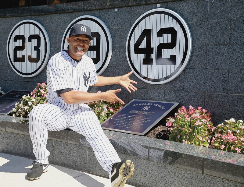 Mariano Rivera sitting next to his retired jersey number at Monument Park. 