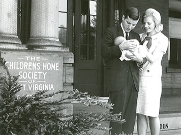 A young couple with their adopted child outside the Children's Home Society.