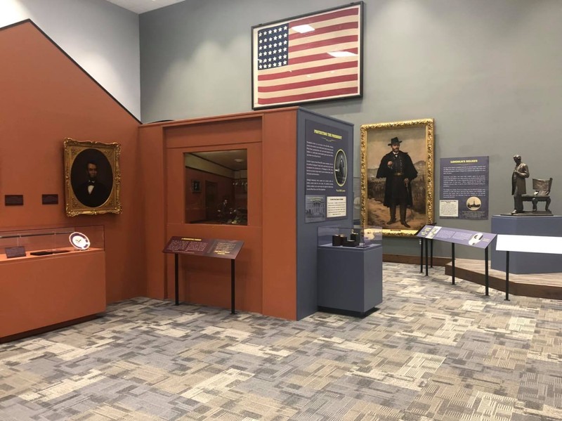 Entrance to the Last Days of Lincoln, showing a diorama, an American flag that flew over Lincoln's casket, and an oil painting of Ulysses S. Grant.