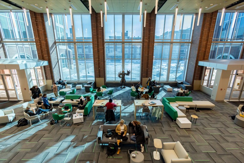 Students sitting at tables and couches with statue of a hawk in the background