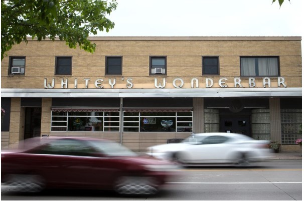 Yellow brick side of of building with "Whitey's Wonderbar" in large letters above the aluminum awning.