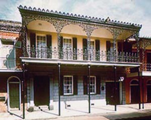 The Gallier House features four iron arches on the balcony that reach up to the roof. The balcony is held up by four pillars.