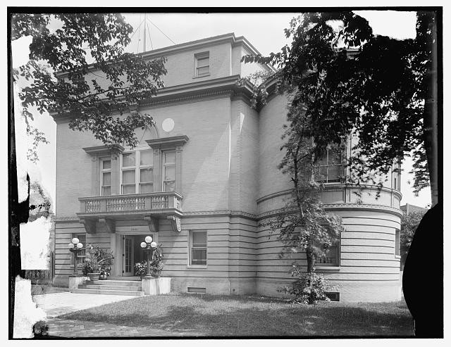 Glass plate negative of New Hampshire Avenue facade, framed by trees.