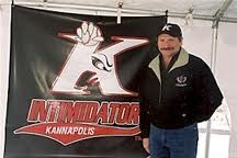 Dale Earnhardt standing in front of logo he inspired