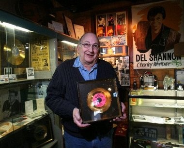 Curator holding a Del Shannon gold record.