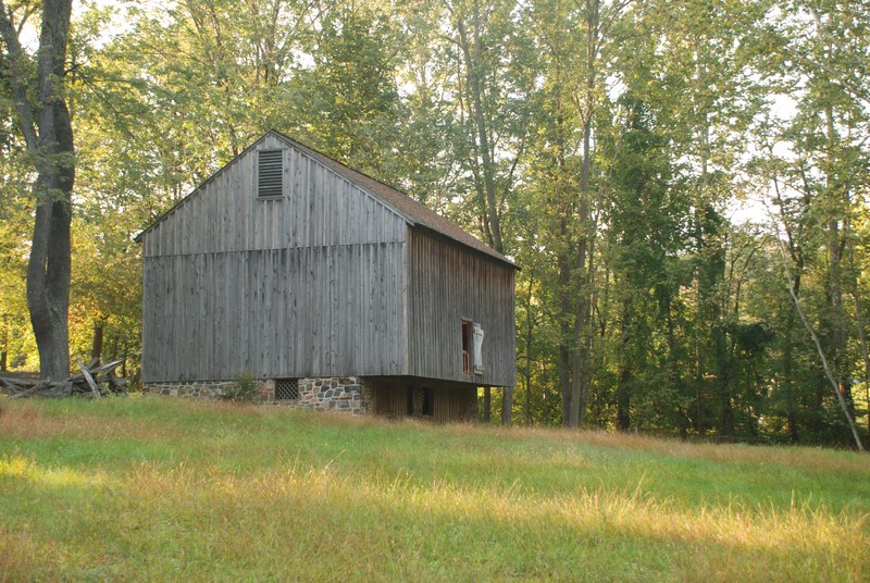 Image of a barn with wooden siding and a stone lower level, built into a hillside