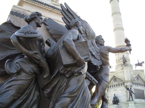 Bronze statues symbolizing Knowledge, Legislature, and Financial Prosperity, found on one side of the monument.