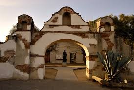 The reconstructed archway/bell tower of San Miguel Arcangel. The statue in the background is of Father Junipero Serra, original founder of the California missions, but who had died several years before San Miguel's establishment.