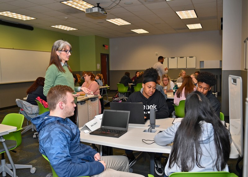 Students and instructors work in small groups with laptops and dry erase boards