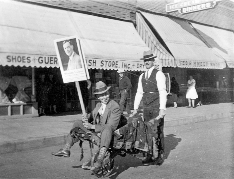 men on street with Ted's Sweet Shop in background