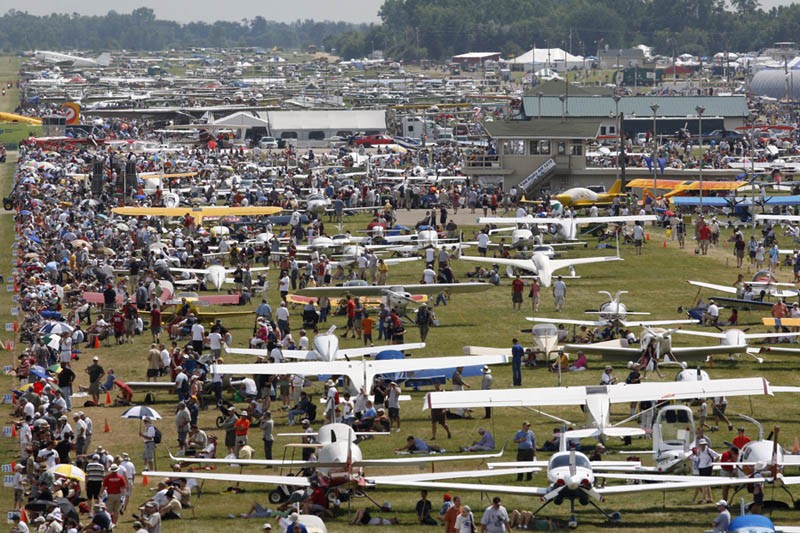 Crowds stroll through the grounds where aircraft are parked.