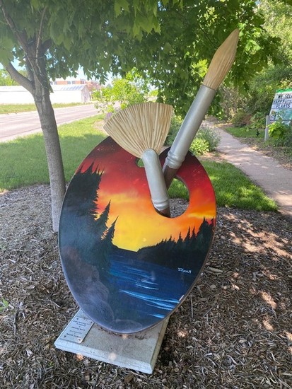 Painted by Jeremy Koch Located at Natural Escapes Jeremy Koch was born and raised in Cozad. After graduating from Concordia University, with a bachelor’s degree in Studio Art with an emphasis in Landscape Design, he and his wife, Bailey, moved back to Cozad. They started Natural Escapes, a destination garden center and landscape installation company, in July 2006 allowing customers to “Experience Nature.” They have two wonderful sons, Hudson and Asher. Jeremy worked closely with the icon committee and the designers at Icon Poly to create the original shape of the icon you see now personalized by artists all over town. The inspiration behind the art pallet icon Jeremy created was his love for spending time outdoors and watching the beauty God continually provides for all to enjoy.