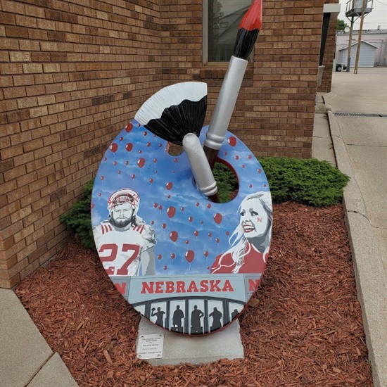 Painted by Patrick Milne Located in front of Cozad Telephone Company Patrick Milne is a 38-year-old spray paint artist from North Platte where he currently works for the City of North Platte. He has been painting for approximately four years. His artwork features Cornhusker punter Sam Foltz, who passed away in 2016, and current University of Nebraska-Lincoln cheerleader Meredith Bowen. Patrick is married to his lovely wife, Jenn. In addition to his artistic endeavors, Patrick is also a volunteer at “Fur the Love of PAWS” animal rescue.