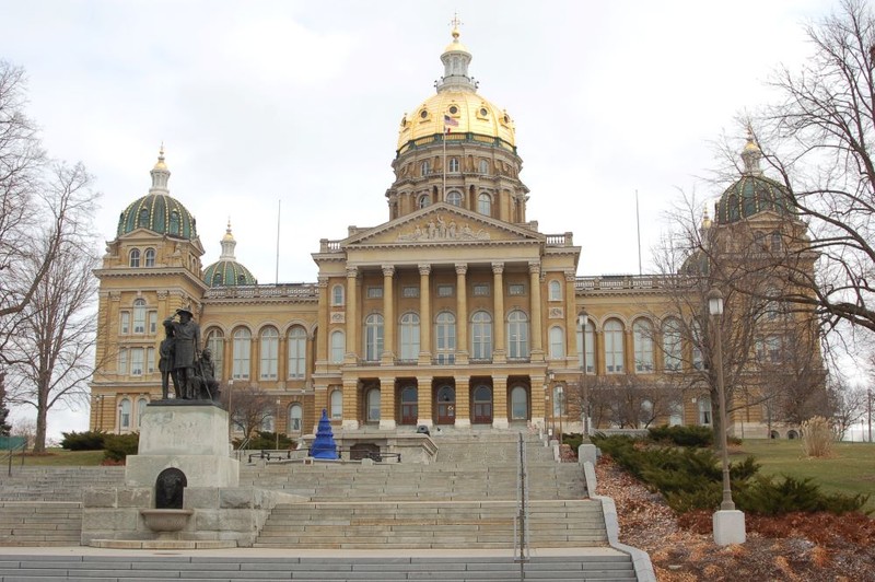 Pillared building with gold dome atop it. Statue and stairs in front of the building.