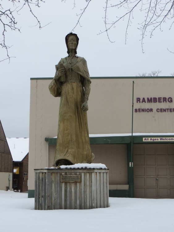 golden statue of a woman in front of a concrete block building