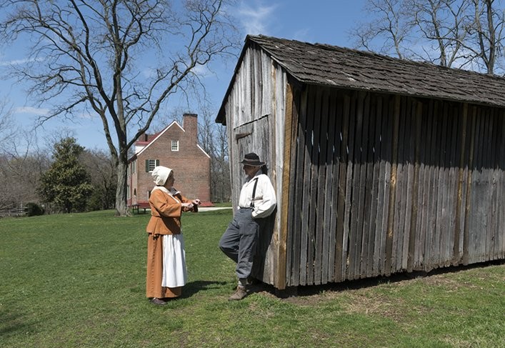 Period actors relax by an out building.  