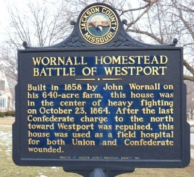 Picture of the historical marker, with some trees in the background. Marker Inscription: Built in 1858 by John Wornall on his 640-acre farm, this house was in the center of heavy fighting on October 23, 1864. After the last Confederate charge to the North toward Westport was repulsed, this house was used as a field hospital for both union and Confederate wounded.