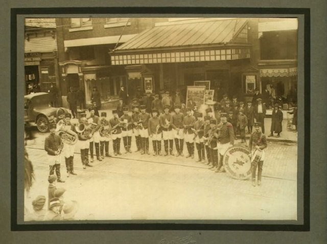 A band performs in front of the Rowland. Believed to have been taken during its opening in 1917. Other sources state that this photo was taken on the 1890s when the building was the Pierce Opera House before it was destroyed by fire in 1910.