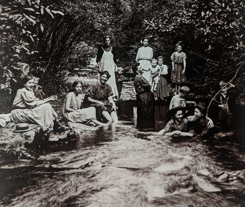 Photo taken by William T. Clarke. Women and children cooling off in creek on a hot day.