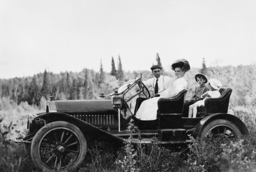Black and white image of man, woman, and two children in automobile