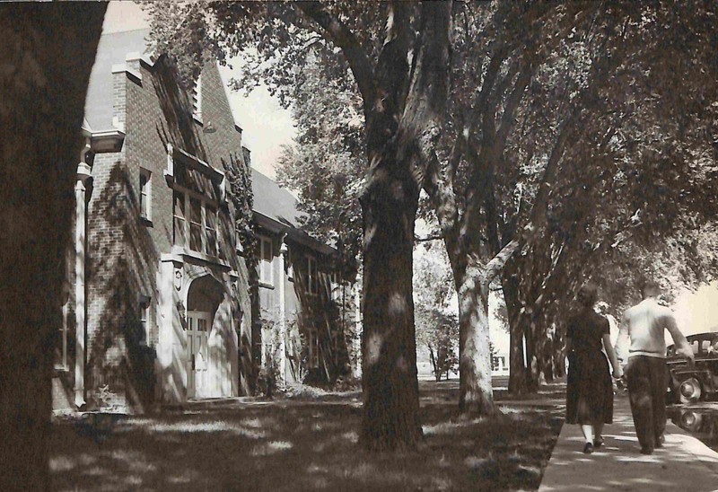 Photo of Quay Hall. A couple walking down the sidewalk holding hands.