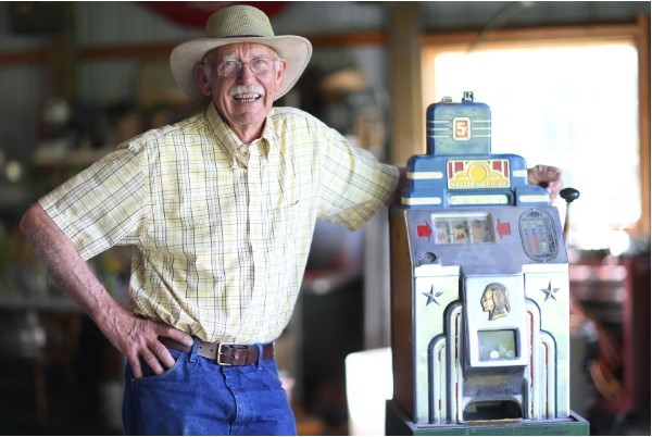 Older man in yellow plaid shirt, blue jeans, and cowboy-style straw hat.