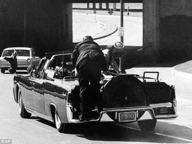 Agent Hill pushing the First Lady back into the the car as she reaches for a piece of her husband's skull