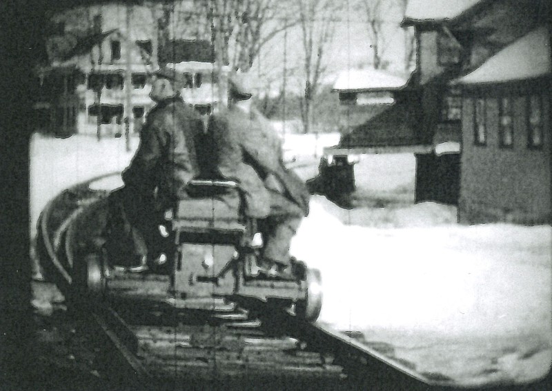 Phil Ball and Irving Hicks rounding the curve of the railroad on a hand car with the Nelson Grain Mill on the right.  From film by Oscar Polhemus, circa 1930