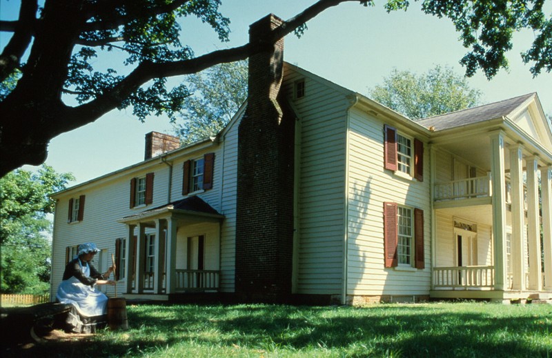 Churning butter in front of the Davis Home.