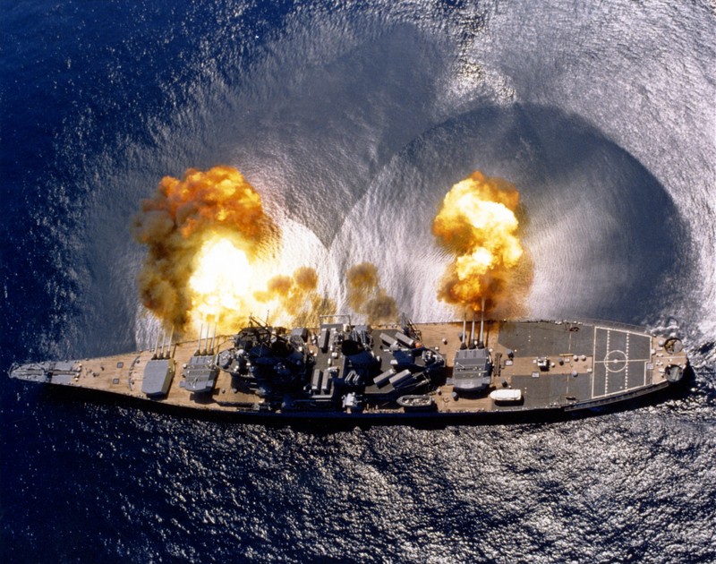 Aerial view of USS Iowa firing her main guns.  Note the shockwave visible on the water.