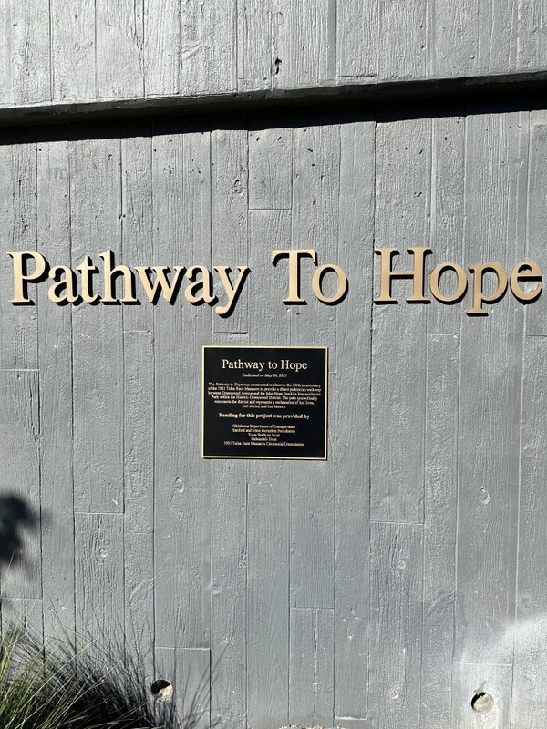 Large Text: Pathway to Hope, Plaque: Pathway to Hope Dedicated on May 28, 2021 The Pathway to Hope was constructed to observe the 100th Anniversary of the 1921 Tulsa Race Massacre to provide a direct pedestrian walkway between Greenwood Avenue and the John Hope Franklin Reconciliation Park within the Historic Greenwood District. The path symbolically reconnects the district and represents a reclamation of lost lives, lost stories, and lost history. Funding for this project was provided by Oklahoma Department of Transportation, Stanford and Irene Burnstein Foundation, Tulsa Stadium Trust, Helmerich Trust, 1921 Tulsa Race Massacre Centennial Commission