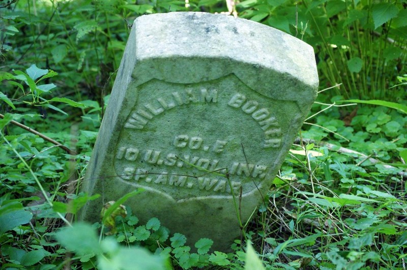 Headstone of Spanish-American War Veteran, William Booker, slumped over in the woods