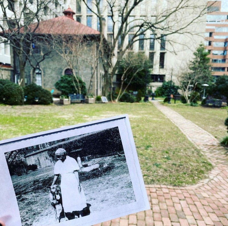 Black and white photo of a Black woman and a dog held in front of current day Heurich Museum garden.