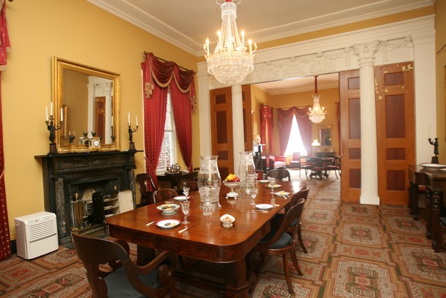 The dining room within the house features the original table, crystal chandelier, and pocket doors.