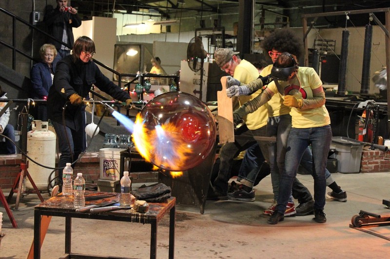 Artists making a large glass piece in the glass studio