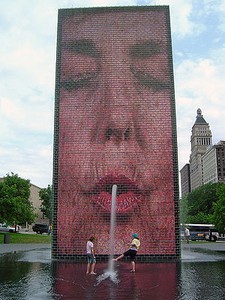 One of the fountain's faces spouting water on park goers