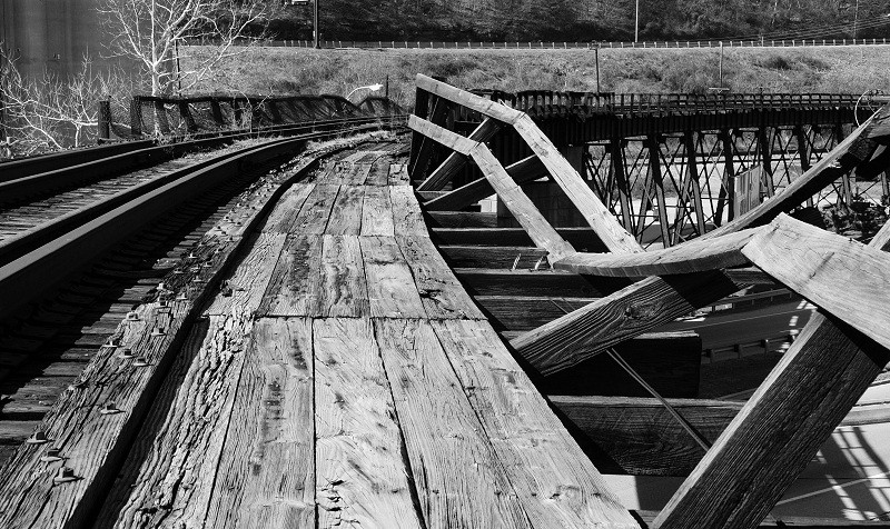 A view of the bridge in its current state. This photo shows leaning support beams and uneven tracks.