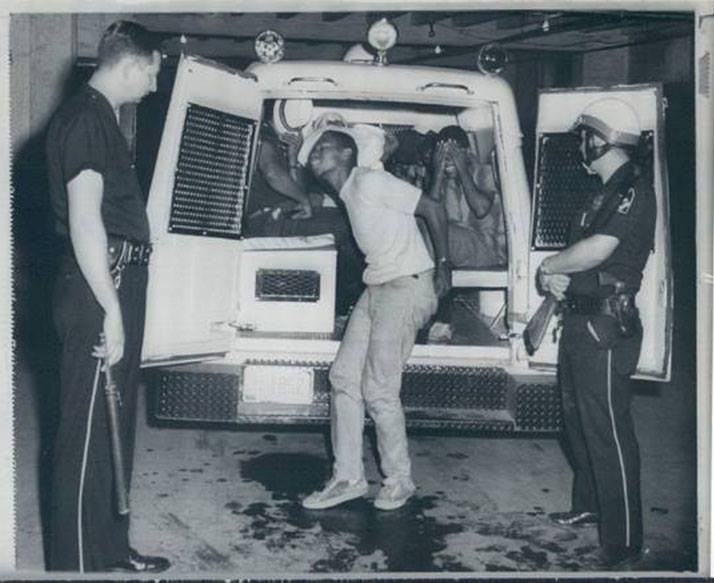 In this photo, Black youth who were involved in the the 1 August, 1966 riot are being arrested and taken into custody.
