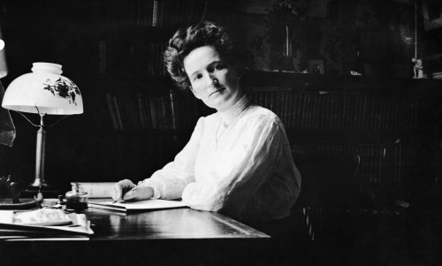 Black and white image of woman writing at a desk