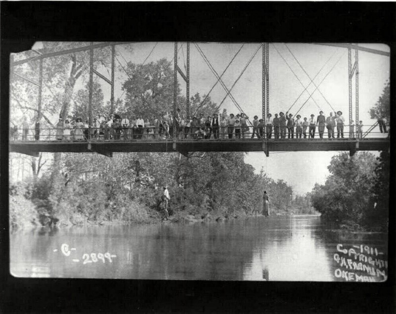 Photograph of Laura and L.D. Nelson along with lynch mob and observers on the Schoolton Bridge after the lynching. 