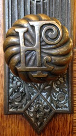 Detail of a doorknob with the library logo "HPL"