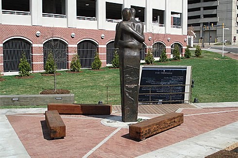 The three wooden benches symbolize the triangular routes of the slave trade, while the embracing figures represent a commitment to healing racial wounds.