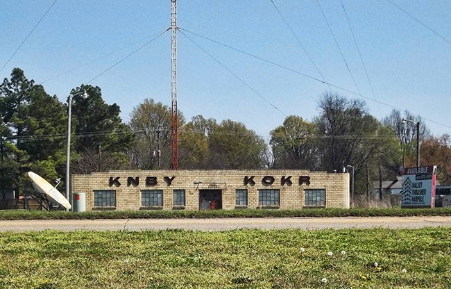 A colored photo of an old radio station with a radio tower.