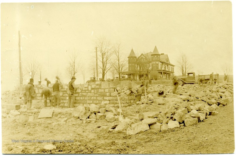 Builders setting the foundation of Admin - note Arthur Mansion behind it