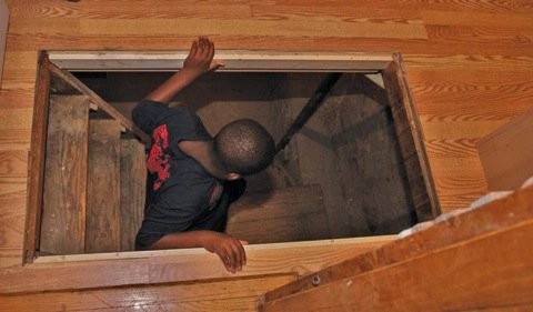 On the Underground Railroad Tour, a boy investigates a small room below a trap door, believed to house fugitive slaves