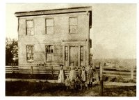 A historical photo of the Kellogg-Warden house when it was in Lower Town, with the Greiner family standing in front. The Greiners owned the home for 100 years.