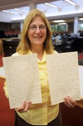 An archivist holds up original copies of university archives