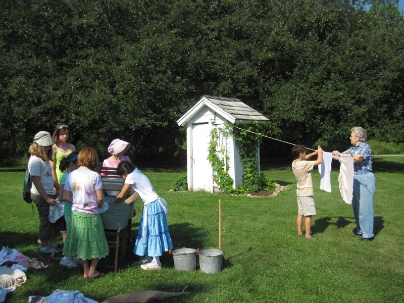 Schoolchildren learn how to wash clothes using a washtub and hand wringer