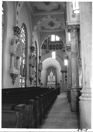 Interior view of church showing altar, elaborate ceiling and wall moldings, and pews