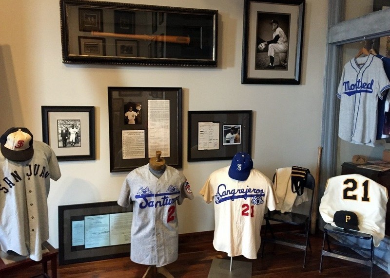 Various jerseys worn by Clemente with pictures of the right fielder in the background.